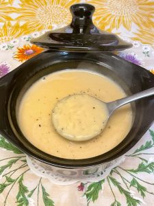 Rice cheese soup in a soup bowl with spoon lifting up some soup.
