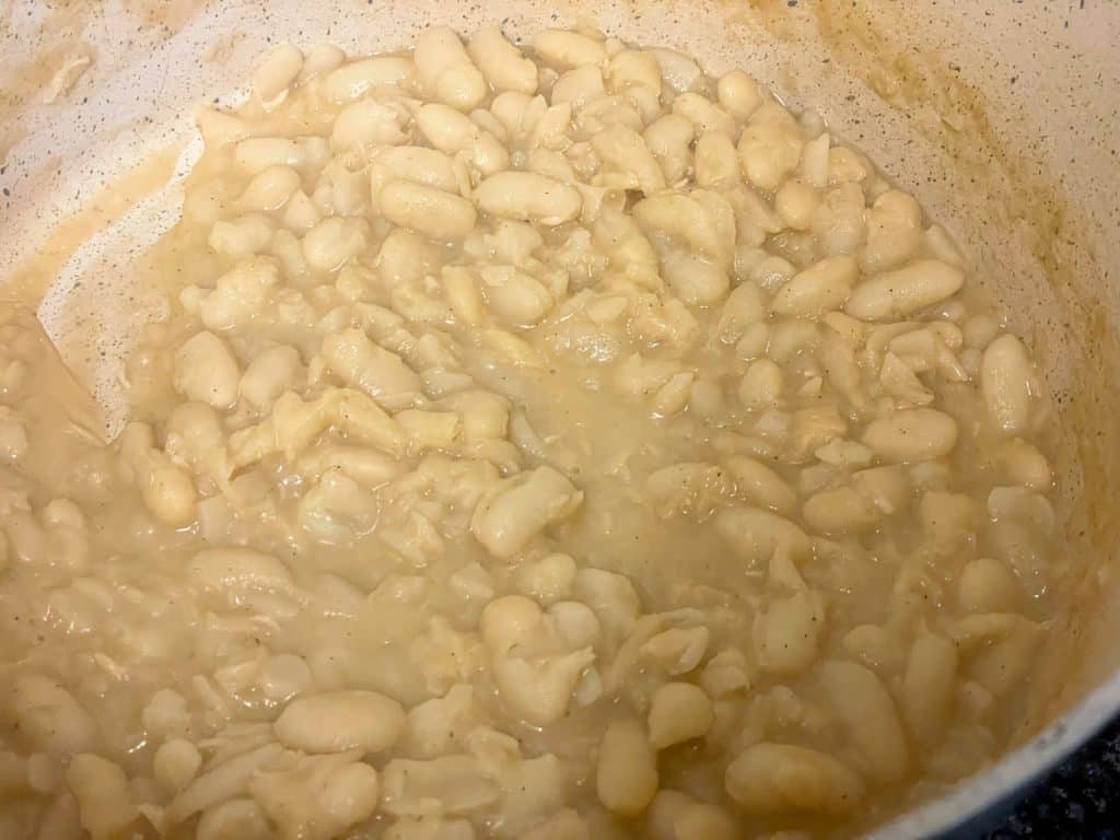 White beans in saucepan with milk.