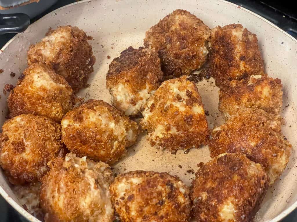 Bean croquettes frying in pan.