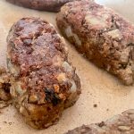 Lentil sausages cooking in pan.