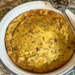 Cheese pudding baked and still in baking dish with a serving spoon to the side.